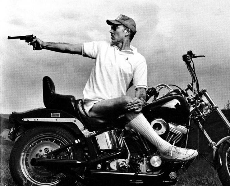 Hunter S. Thompson on a motorcycle with a gun