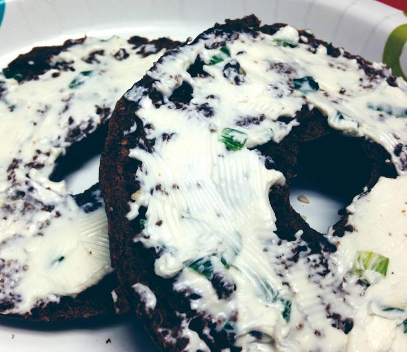 Whipped cream cheese with chives on top of a pumpernickel bagel